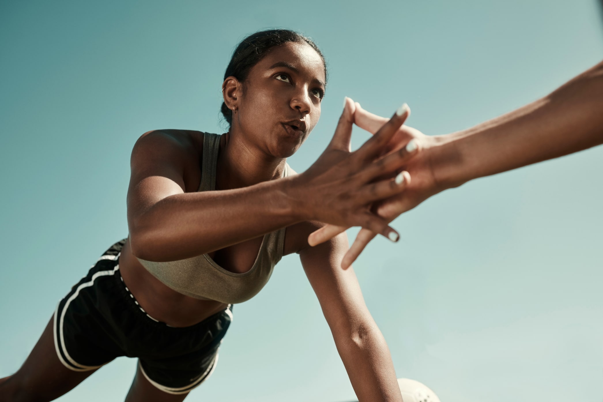 Athlete touching another athlete's hand in a race to signal their turn to run