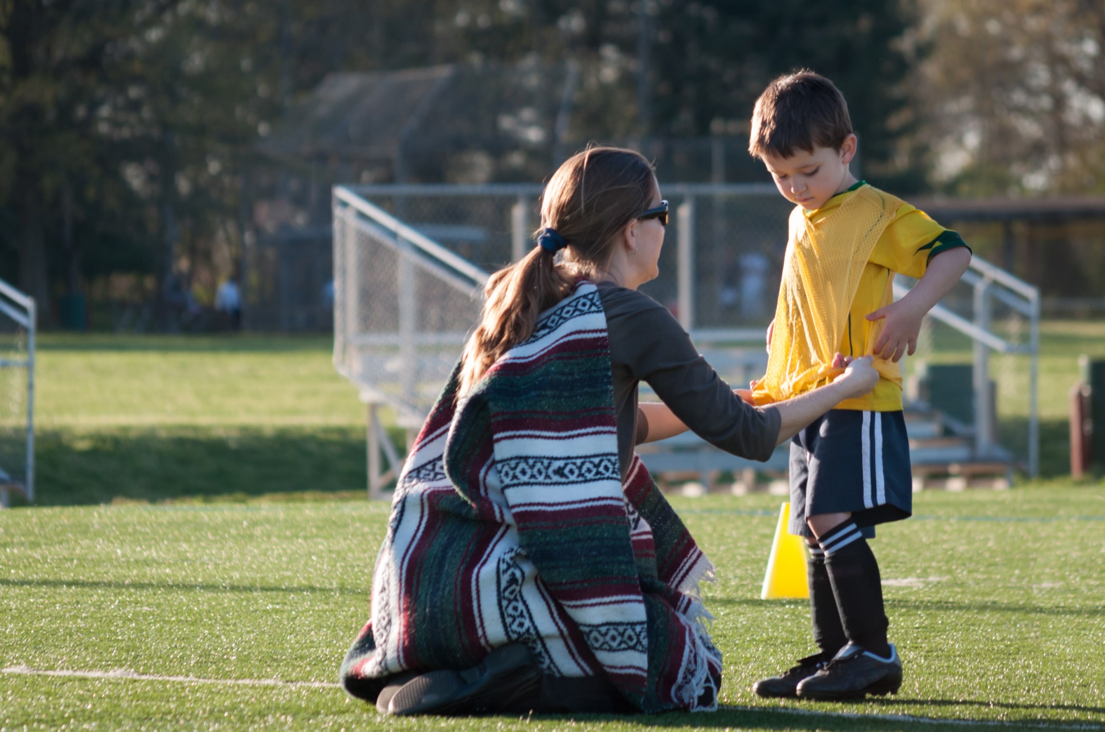 Adult assisting a youth in soccer