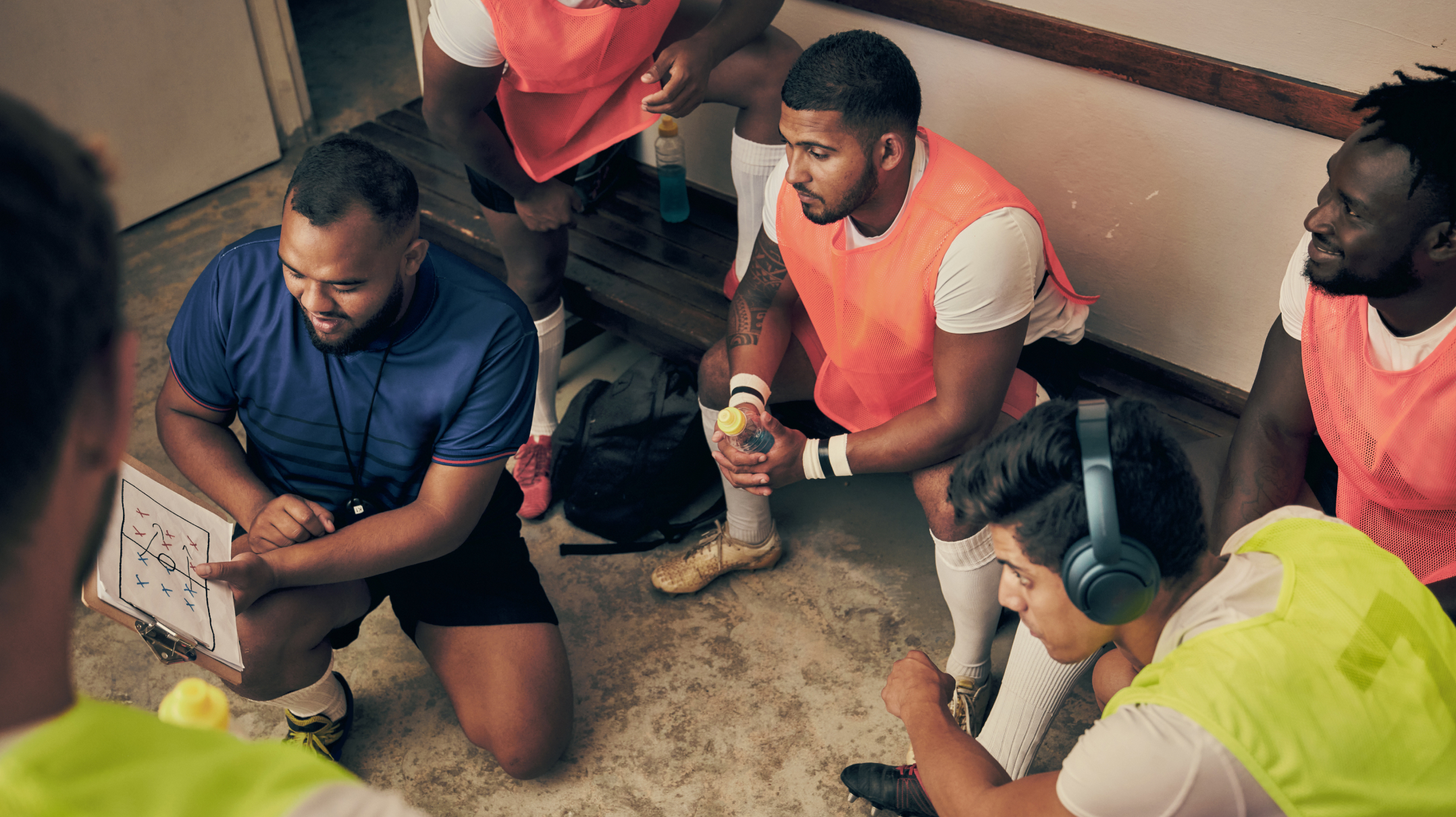 A group of athletes reviewing a play in a locker room.