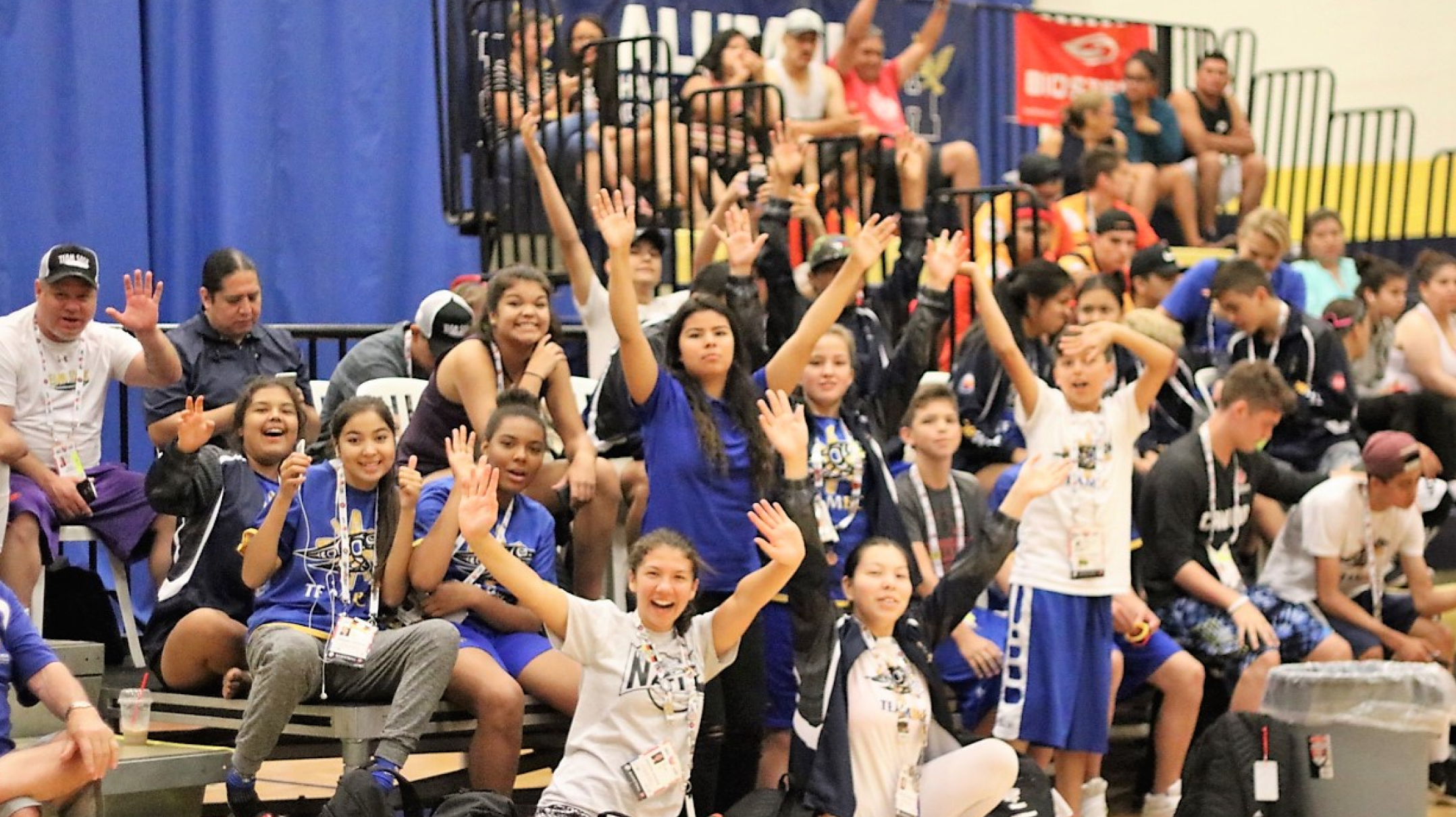 Group of students and athletes celebrating during game.