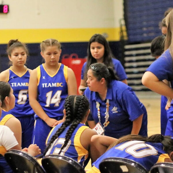 Coach speaking to basketball team during game.