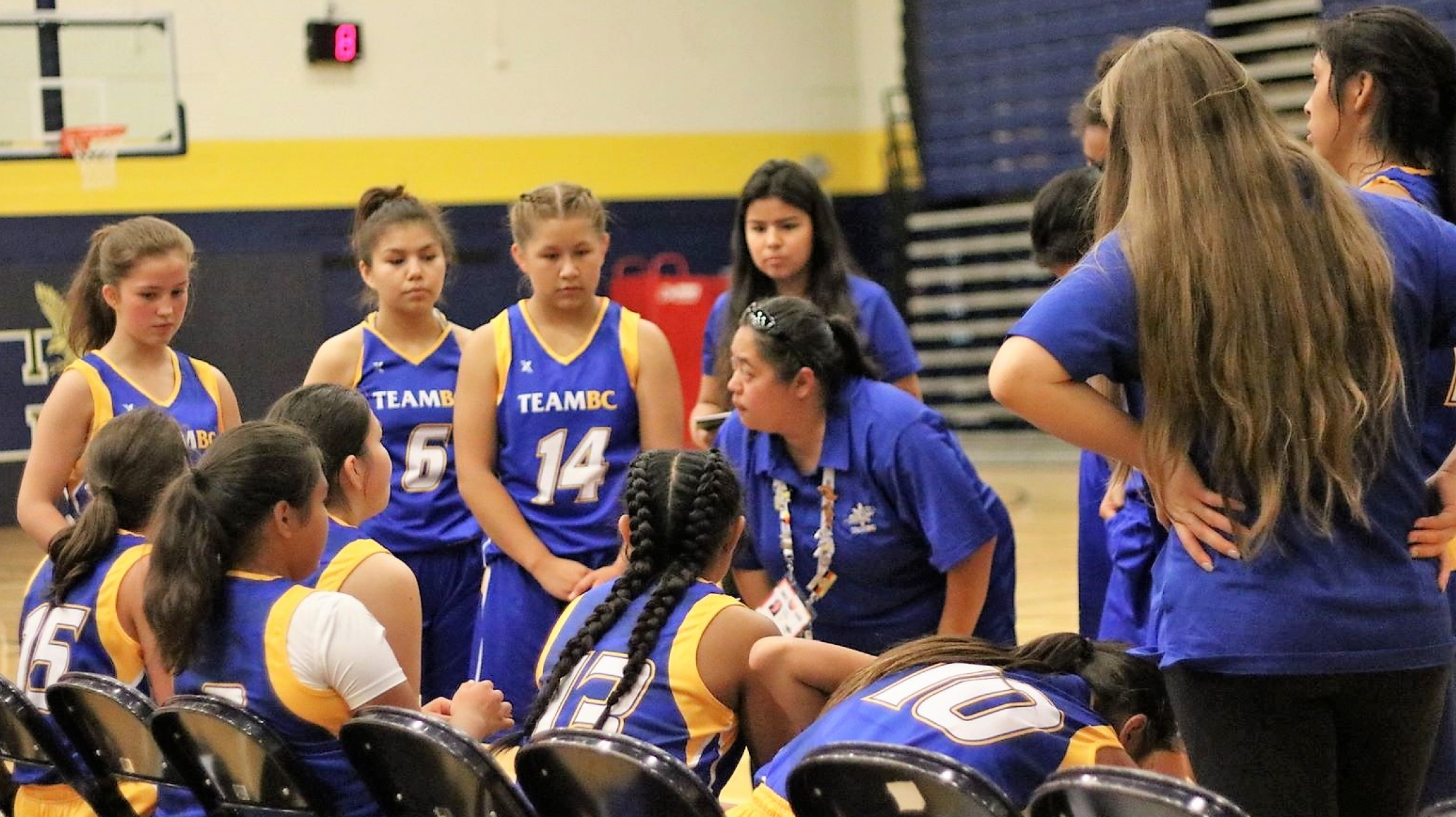 Coach speaking to basketball team during game.