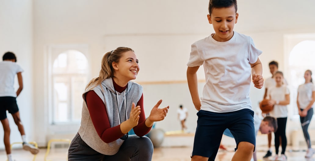 Adult giving supportive encouragement to a young child at a gym course