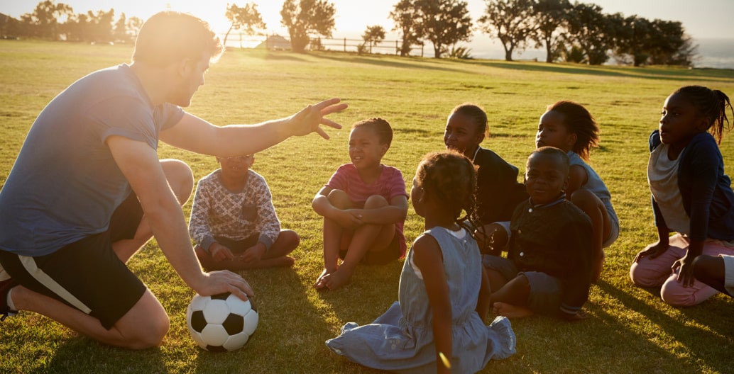 Soccer coach providing feedback and lessons to a group of young athletes