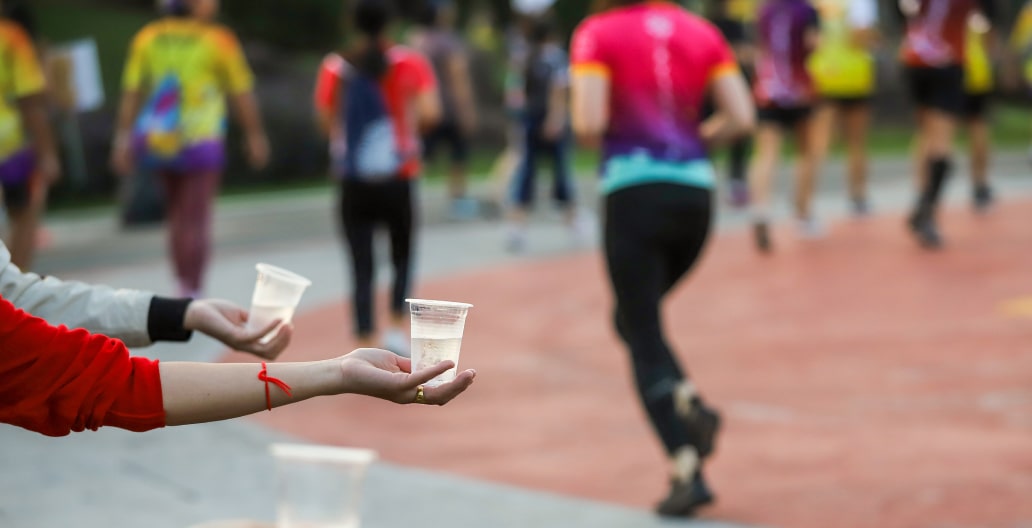 Volunteers handing out cups of water to runners at a marathon